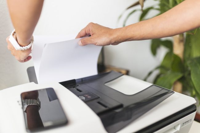 Person feeding paper into printer - stop using fax